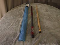 Full view of the two-piece pool cue laid flat next to blue soft case