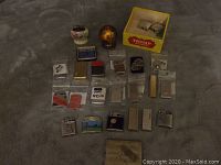 Full view of the lot showing 16+ vintage lighters, a cigarette case, and a Trump cigar box.
