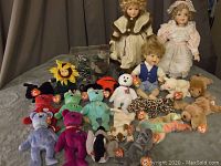 Full lot showing 13 various Ty Beanie Babies plush toys, 3 vintage dolls, and 2 Anne Geddes dolls on table