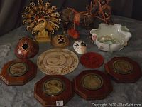 Photo showing full layout of mixed decor items including wood engravings, pottery, figurine horse, shell dish, masks, and sculpture