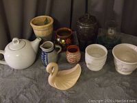 Overview of the lot showing various pottery and ceramic items including teapot, flower pots, pitchers, and decorative swan.