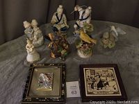 Photo of nine assorted figurines and two framed plaques arranged on a soft surface