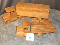 Front and side view of two hand crafted wooden trucks on a soft surface, showing natural wood grain and overall build.