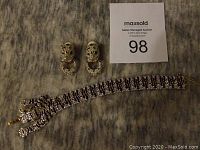 Photo shows the Ivana Trump panther bracelet and matching earrings laid flat on a textured surface.