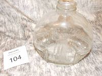 Close-up photo of the clear glass bottle with embossed Chicago World's Fair and Century of Progress 1833-1933 text and building designs, showing some wear and no lid.