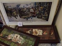 Three framed pictures laid out, largest shows snowy historical scene with sled and crowd, smaller photos show golf items and golf cards