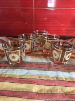 Set of five Libbey whiskey rocks glasses on striped cloth background.