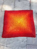 Full top view of the retro accent rug showing a fuzzy textured sunburst gradient pattern from yellow center to red edges.
