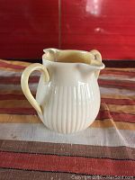 Front view showing the ivory double spouted creamer with ribbed body and curved handle.