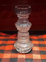Front view of clear glass vase with textured bubbly and ridged design standing on checkered cloth.