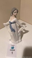 Photo of Lladro porcelain figurine of woman in white dress with blue sash, front and side views visible