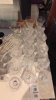Top view of 16 clear glass drinking glasses and 1 glass ice holder arranged on a table.