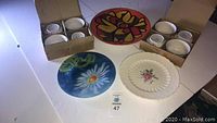 8 Mikasa white dessert bowls boxed, and 3 decorative plates laid out including floral and abstract designs