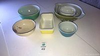 Overview of all seven bowls including six vintage Pyrex mixing bowls and bakeware dishes plus one floral Coalport bowl.