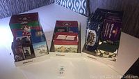 Lot of 10 assorted Christmas village decoration boxes displayed on a table, contents unchecked.