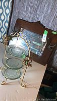 Wood-framed vintage mirror and grapevine motif metal serving piece with three decorative glass plates.