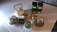 Full assortment including tea cups and saucers, teapot, cream and sugar set, miniature set, and tea jars on table.
