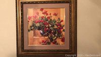 Framed floral artwork in decorative gold-tone frame, showing red flowers in a pot with warm background.