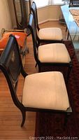 Three chairs in a row showing seat upholstery and back cane detail