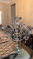 Full view of the metal candelabra showing all candle arms with glass holders and bead chains on a table.
