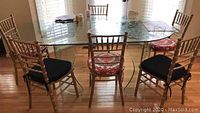 Photo showing full dining table with four floral cushioned chairs and two black cushioned chairs around it.