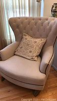 Front view of chair showing tufted back, seat cushion and included pillow