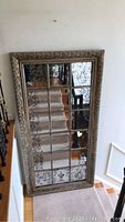 Full front view of mirror leaning against wall on staircase landing.