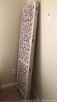 View of one of the carved wooden panels showing the floral interior detailing in a distressed white finish.