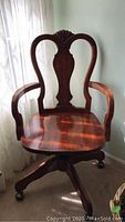 Front view of vintage wooden bankers desk chair showing carved backrest, armrests and seat