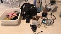 Lot items arranged on floor showing camera, camcorder bag, speakers, CD boombox, cables, and accessories
