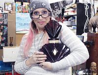 Photo showing woman holding the large dark purple fan-shaped perfume bottle to demonstrate size and shape.