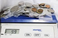 Assorted coins weighing approximately 9.9 ounces on a digital scale.