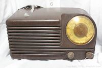 Front angled view of brown vintage 1940s Bakelite radio with gold dial and two control knobs.