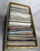 Top-down view of a cardboard box filled with over 160 comic books in protective sleeves