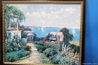 Close-up of framed textured print showing coastal scene with houses, sailboats, and greenery.