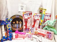 Collection of vintage, brand new PEZ dispensers in original packaging arranged with a green Beanie Baby bunny plush. Shows Elvis Presley 3-piece set in collector's tin, Valentine and Easter themed PEZ, and other assorted dispensers.