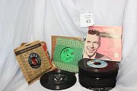 Side view of stacked 45 RPM records with Frank Sinatra record on top in pink 'Young at Heart' sleeve, several other records in vintage sleeves including Decca, Brunswick, and others.