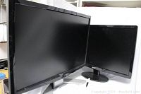 Front view showing two black Acer computer monitors side by side, one significantly larger than the other, both powered off.
