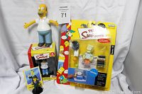 Full lot overview showing Tom Hanks Homer figure, boxed Homer figure, Bart Simpson packaged figure and other small collectibles
