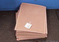Stack of pink rectangular woven carpet door mats with rounded corners, showing the mats stacked flat and tagged with a number 79 label.