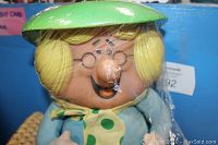 Close-up front view of the doll's face and upper body wrapped in plastic.