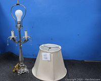 Vintage table lamp base without lampshade, showing light bulb holder and crystal decorations hanging from candle arms.