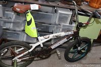 Left side view showing the Rebel Mongoose branding, mag wheels, brown seat, and attached neon yellow safety vest.