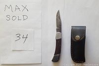 Photo of Damascus folding knife with wood handle, showing the patterned blade and accompanying leather sheath.