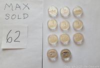 Eleven silver coins in clear plastic capsules arranged in grid