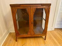 Front view of antique wooden two-door glass cabinet with decorative trims and glass panels.