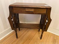 Front view of antique wooden telephone table showing drawer and side racks