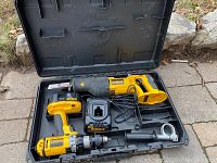 Open case showing cordless reciprocating saw, cordless drill driver, battery charger, and 18V battery inside molded compartments.