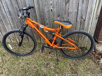 Full side view of the orange Nakamura Monster child's mountain bike showing the full frame, wheels, and suspension components.