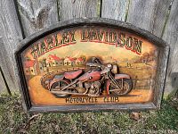 Front view of the Harley Davidson Motorcycle Club wooden sign with 3D relief motorcycle and painted village scene.